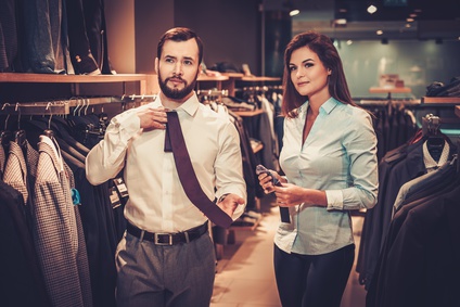 Confident handsome man with beard choosing a tie in a suit shop.